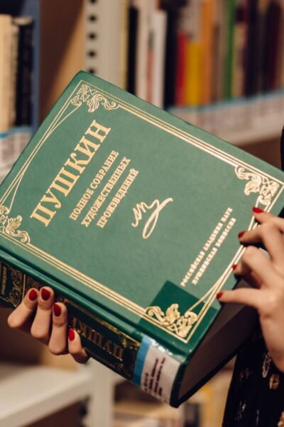 A woman holds a Russian literature book in a library, showcasing a focused study environment.