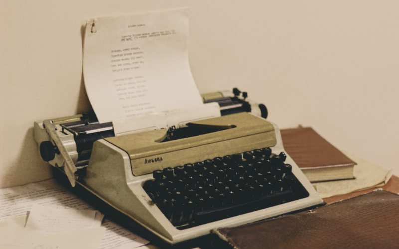 A classic typewriter with paper, surrounded by books, evokes retro vibes.