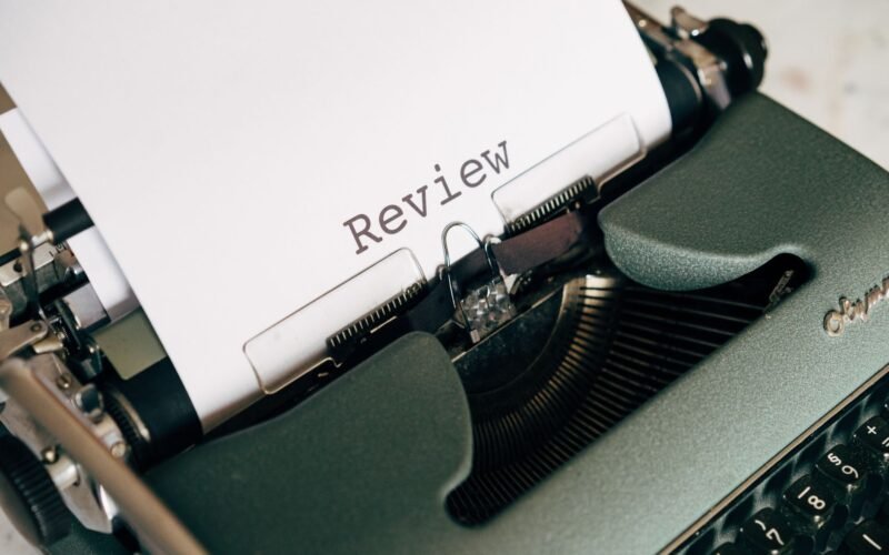 Close-up of an antique typewriter printing the word 'Review' on white paper.