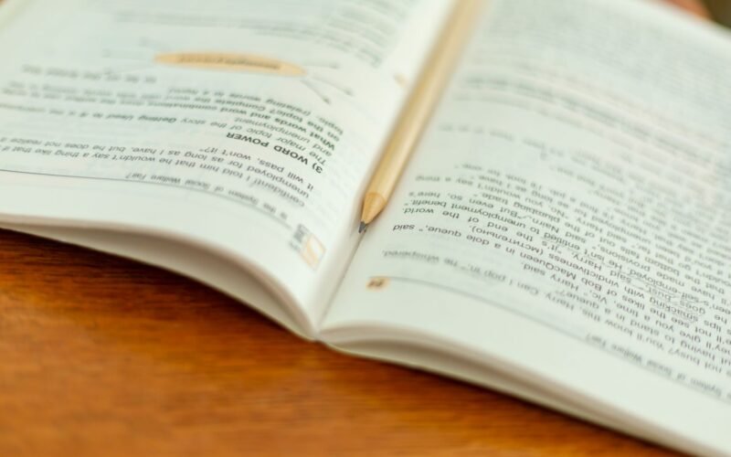 An open book with a pencil on a wooden table, perfect for educational themes.