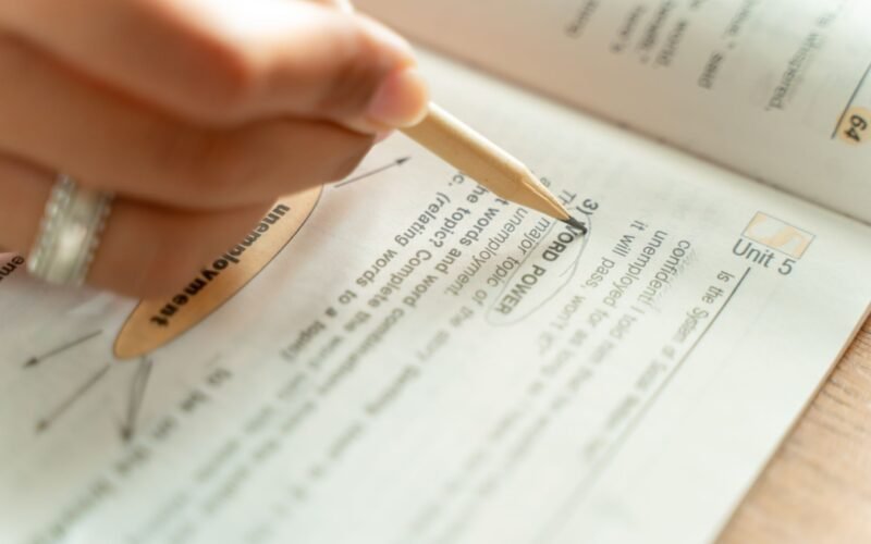 Close-up of a woman writing notes in a textbook, focusing on education and learning.